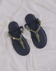Black leather sandals with green rope straps by Flowze FLO on white fabric background.