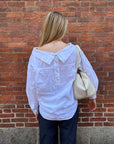 Rachel Comey Dallbey Top in cream, styled with a cream bag by a brick wall for a relaxed, modern look.