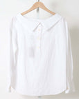 White Rachel Comey Dallbey Top, cotton long-sleeve blouse on wooden hanger, neutral background.