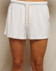 A person wears Perfectwhitetee's Summer Loop Terry Sweat Shorts—white with a beige drawstring—against a plain, light background. The photo is cropped from waist to mid-thigh.