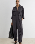 Charcoal gray gabardine Meet Jumpsuit with collar, zip front, flap pockets, and cuffed ankles, paired with a black tote.
