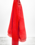 A vibrant red towel hanging on a hook against a white background with a shadow on the floor, displaying the text "Lucky Rabbits Sweatshirt" at the bottom in a bungalow by Free City (sparrow, LLC).