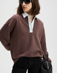 The Classic Rugby Polo by Sold Out NYC in a casual, modern style paired with black pants and a sleek handbag.