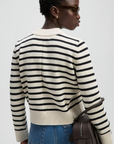 The Favorite Crew sweater and jeans by Sold Out NYC, worn casually with sunglasses and a brown bag, urban setting.