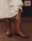 The Great Inc. Southwest Cowboy Boot in white lace paired with a rustic wood floor and horse art backdrop.