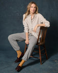 The Fleece Stadium Sweatpant on a seated woman wearing a striped shirt, mustard socks, and loafers in a wooden chair.