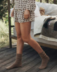 Flannel Smocked Sleep Short in horse medallion print worn with tan ribbed socks on a wooden deck.