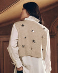 Embellished beige sweater vest with floral details worn over a white collared shirt by Bungalow Furniture & Accessories.