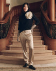 The Rayon Jersey Turtleneck with a large fabric flower worn with light trousers on a curved staircase.