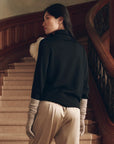 The Rayon Jersey Turtleneck and long gloves worn by a woman on a staircase, holiday style by Bungalow.