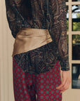 Smooth tan Wrap Scarf layered over a patterned blouse and vintage-style geometric print pants.