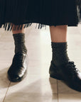 The Lurex Sock in black glittery material styled with black leather lace-up shoes.