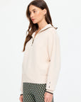 The Upside KAIRO HALF ZIP KNIT sweater and patterned pants in a modern, minimalist setting, side profile view.