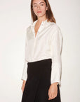 Loose-fit, off-white Roseanna Chemises Shirt with a stand-up collar tucked into a black wrap skirt.