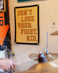 Yellow motivational camp flag with bold black text by Faire, adds character to a modern wall; ideal for home decor.