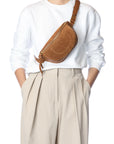 Jerome Dreyfuss Lino Banane bag styled with a white sweater and beige pleated pants, hands in pockets.