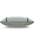 The Elspeth Gimp Pillow by Eastern Accents is shown from the side against a white background, featuring light gray cotton fabric with emerald trim and small bronze studs.