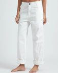 A person wears loose fit, high-waisted ASKK chino twill pants with rolled cuffs in white, standing barefoot against a plain light background.
