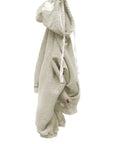 The BASIC GOODNESS HOODIE by Free City (sparrow, LLC) is a light gray, oversized pullover with white drawstrings, a front pocket, and a small red tag near the hem, shown hanging on a hook against a white background.