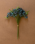 The CHAL1047 Blueberry Bundle by Kalalou, Inc features green stems with clusters of dark blue berries and fern-like leaves, all secured with a rubber band and displayed on a plain brown background.