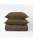 The Bruno Duvet Cover Queen by Amity Home, featuring brown fabric with thin vertical white stripes, is crafted from soft cotton and displayed folded with matching pillows against a plain white background for modern elegance.