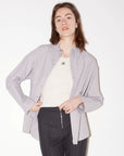 Lavender striped Roseanna Chemises shirt worn unbuttoned over a cream tank and dark grey trousers.