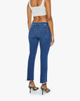 A person wearing a beige crop top, black high-heeled sandals, and Mother’s Mid Rise Dazzler Ankle Fray jeans is standing facing away, highlighting the back details of the jeans.