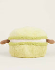 The Faire Green Macaroon Warmie is a light green, microwavable plush toy with small brown arms for sensory comfort, shown against a plain off-white background.