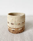Small round basket with natural and brown stripes, handmade by Faire, Mkongo style, textured surface.