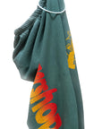 A green Artyard Yumm OG Sweatpant by Free City (sparrow, LLC) with yellow and red partially visible text, hand-screen printed, is shown hanging on a white plastic hanger against a white background.