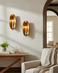 Faire Brass Wall Candle Sconce brings warmth to a bright, airy living room with white accents and an arched doorway.