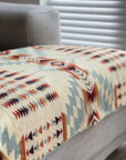 Secoya Throw in Vibrant Mint, a multicolored geometric blanket draped on a gray sofa at Bungalow Furniture & Accessories.