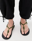 Flowze FLO black pants styled with green rope sandals, light background; Bungalow Furniture & Accessories.