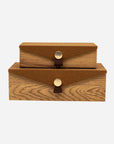 Two stacked Harriett Box wood grain storage boxes with brown suede lids and gold button closures by Bungalow.