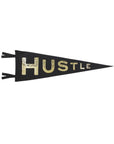 The Faire Hustle Pennant is a black and gold motivational wall decor flag with “HUSTLE” in bold letters and two black ties on the left, perfect to inspire your space.