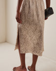 Rachel Comey Mott side-slit skirt styled with a black clutch and open-toe sandals for a modern, chic look.