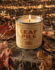 Faire Leaf Pile Soy Candle lit on a tree stump, autumn leaves and warm sunlight evoke cozy fall style.