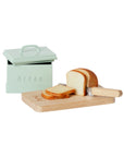 The Maileg Bread box w. utensils by Maileg features a miniature box labeled "Bread," complete with a wooden cutting board, toy loaf, sliced bread, and a toy knife—ideal as a charming dollhouse accessory.