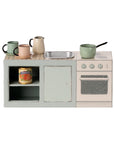The Maileg Kitchen Counter by Maileg features a miniature mouse kitchen set with sink, stovetop, oven, shelf with a canned good, and four pastel cups and pots arranged on the counter—perfect for charming pretend play.
