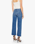 A woman faces away, wearing a white sleeveless top, Mother’s The Mid Rise Maven Flood wide-leg stretch denim jeans with back pockets, and black high-heeled sandals against a plain white background.