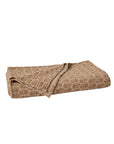 The Mirada Matelasse Blanket by Coyuchi Inc, shown folded on a white background, features light brown organic cotton and a subtle, repeating jacquard matelassé pattern.