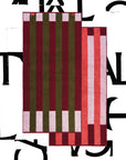 Two Typical Pink/Burgundy Stripe Bath Towels are layered on a white background with bold black lettering. The rectangular towels feature vertical stripes in burgundy, olive green, pink, and red.