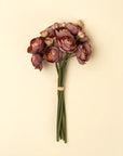 The Faire Ranunculus Bouquet features deep burgundy faux flowers with green stems, tied with light tan string and set against a beige background—ideal for displaying in your favorite decorative vase.
