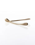 A metallic gold Wishbone /Small decor piece rests on a glossy white surface, casting a soft reflection—an elegant handcrafted aluminum accent.