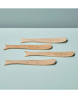 Four whale-shaped mango wood spreaders by Be Home on a light blue surface, playful serveware for kitchen or dining.