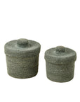 Two round green Indaba Tajine Seagrass Baskets with lids, one large and one small, add Moroccan-inspired style and storage when placed side by side on a white background.