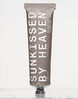 A taupe-colored tube of Faire Tallow Sunscreen SPF 50 stands upright with water droplets on its surface, offering broad-spectrum protection for sensitive skin against a light, reflective background.