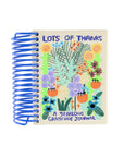 The Faire Gratitude Journal features a blue spiral binding, illustrated flowers and leaves on the cover, and is made in the USA.