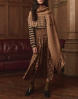 The Big Sweater Fringe Scarf by The Great Inc. styled with playful stripes and polka dots in a cozy indoor setting.
