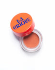 An open round container of Faire's 01 Tinted Lip Balm & Blush with an orange lid, labeled "Faire" in bold blue letters, reveals a warm nude cream infused with hyaluronic acid against a white background.